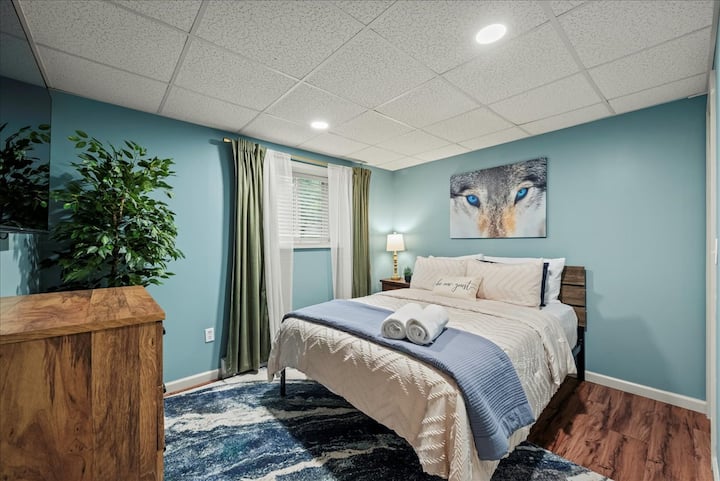 Спална соба 5: нежно сини ѕидови, мебел од топло дрво и голем брачен кревет со удобна постелнина создаваат мирно прибежиште совршено за спокојни ноќи.