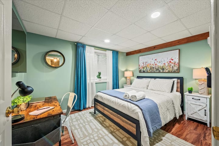 Спална соба 6: меките зелени ѕидови и завесите со океанско-сина боја создаваат свеж, привлечен простор со брачен кревет (широк 150 – 179 см) на кој има мека постелнина и уредно свиткани крпи.