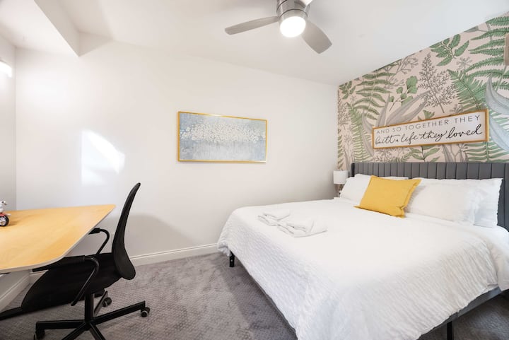 Pokojná spálňa s manželskou posteľou, pracovným stolom a mäkkými prírodnými tónmi.