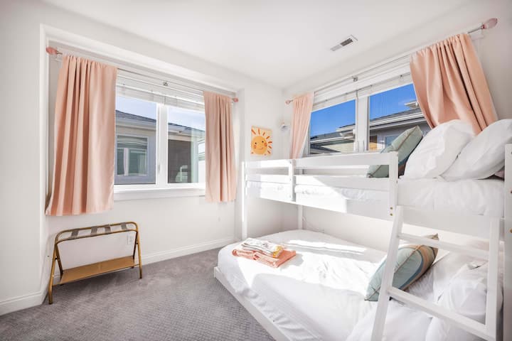 Slnečná detská spálňa s veselými ružovými závesmi a poschodovými posteľami.