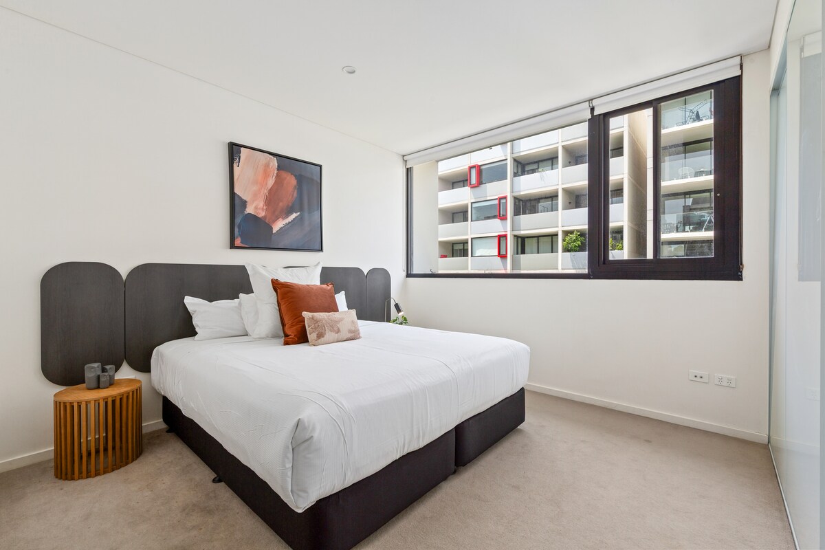 De eerste slaapkamer biedt een rustige ontsnapping met een kingsize bed, warme verlichting en een eigen badkamer voor extra comfort en privacy.