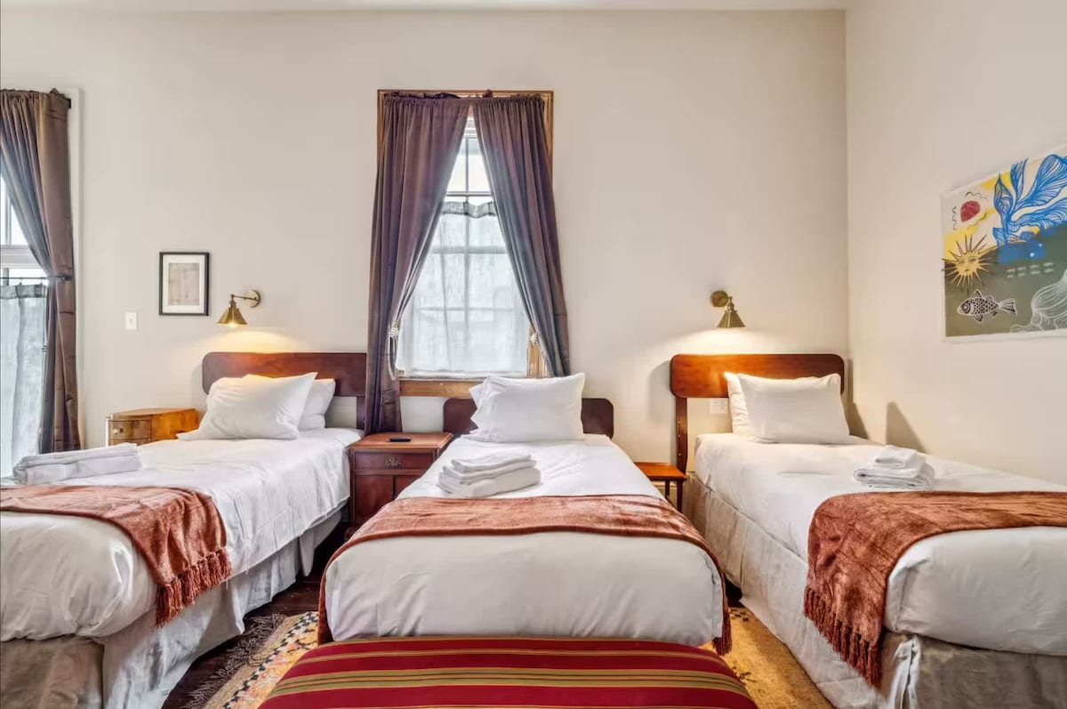 卧室配备三张单人床、复古装饰和柔和的自然光。