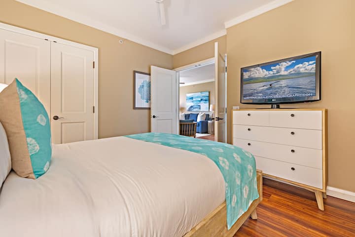 Shijo një dhomë të rehatshme për vizitorë me mure të buta neutrale, një krevat të rehatshëm të veshur me të bardhë të freskët dhe nuanca të kaltra dhe një komo elegante me një televizor të montuar.