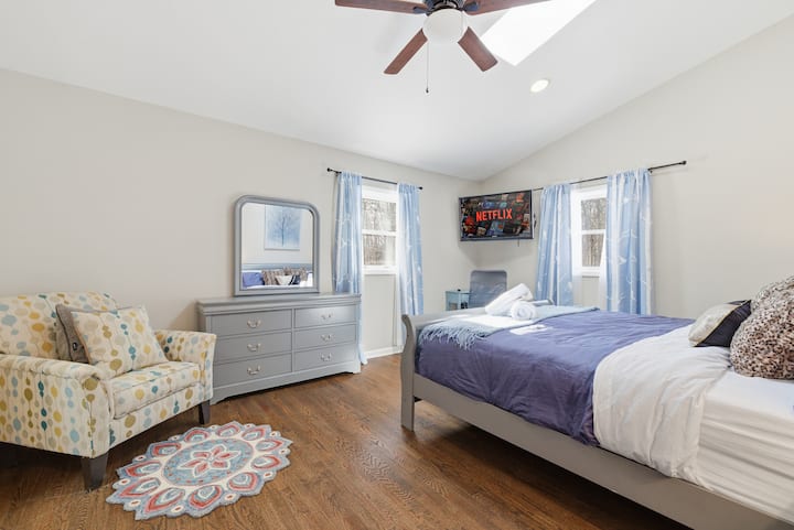 Svetlá spálňa so strešným oknom, televíziou so streamovaním, stropným ventilátorom a útulným sedadlom