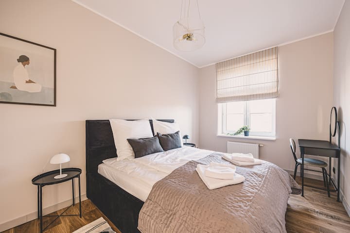 საძინებელი, რომელშიც დგას ელეგანტური საწოლი და ბუნებრივი სინათლეა — ნამდვილი ადგილი დასასვენებლად.