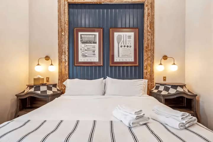 Dormitorio tamaño king con pared decorada en azul marino, molduras de madera desgastada y decoración vintage.