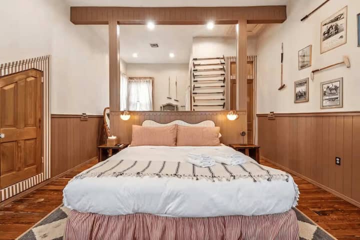Dormitorio con cama tamaño king, detalles de madera cálida y decoración ecuestre vintage.
