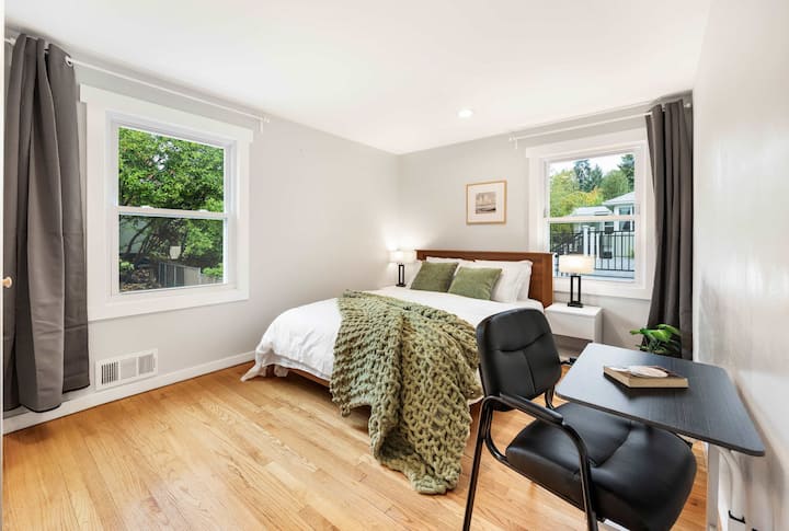 Chambre sereine baignée de lumière naturelle, avec un confortable jeté en tricot vert pour une détente ultime.