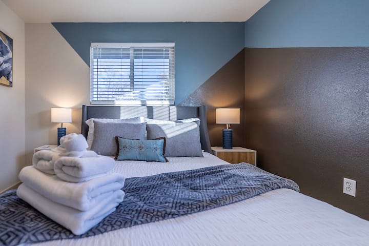 พักผ่อนในสวรรค์แห่งการพักผ่อนที่เตียงควีนไซส์นุ่มสบายต้อนรับคุณ โต๊ะข้างเตียงเก็บสิ่งที่คุณต้องการไว้ใกล้มือ และผนังที่โดดเด่นช่วยเพิ่มความสะดวกสบายและเสน่ห์