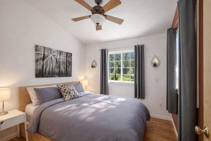 Deslízate pacíficamente en este dormitorio sereno donde las sábanas grises suaves se encuentran con tonos de madera natural, creando tu refugio perfecto.