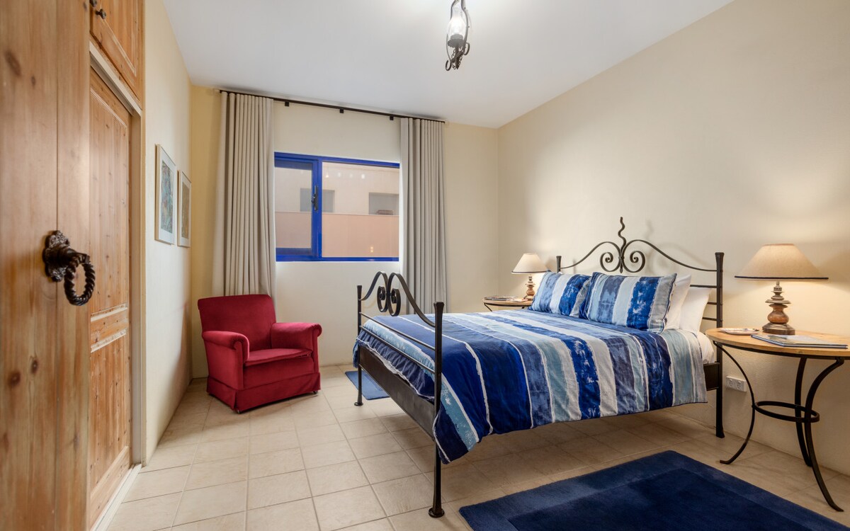 Retírate a una habitación principal relajante donde una cama tamaño queen, colores suaves y sonidos del océano invitan a un descanso profundo.