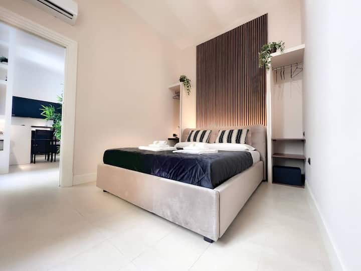 Пространа соба со удобен кревет, осветлено потпирач за глава и интегриран простор за гардероба. Светлите бои и минималистичкиот мебел создаваат уреден и хармоничен простор, во континуитет со дневната соба со отворен план.