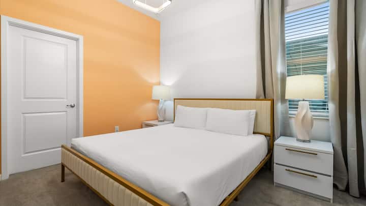 Dormitorio 5 – Habitación king luminosa con tonos naranjas cálidos y una decoración limpia y moderna.