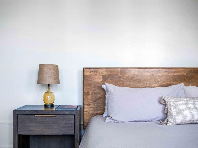 Агол покрај креветот со модерна ламба и удобни перници.