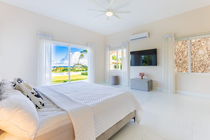 Uși din podea până în tavan care se deschid spre priveliști tropicale.