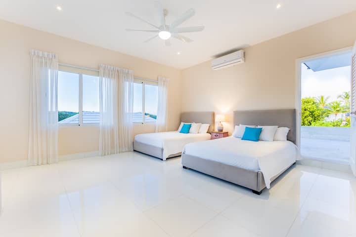 Dormitor luminos pentru oaspeți, cu două paturi matrimoniale „Queen”.