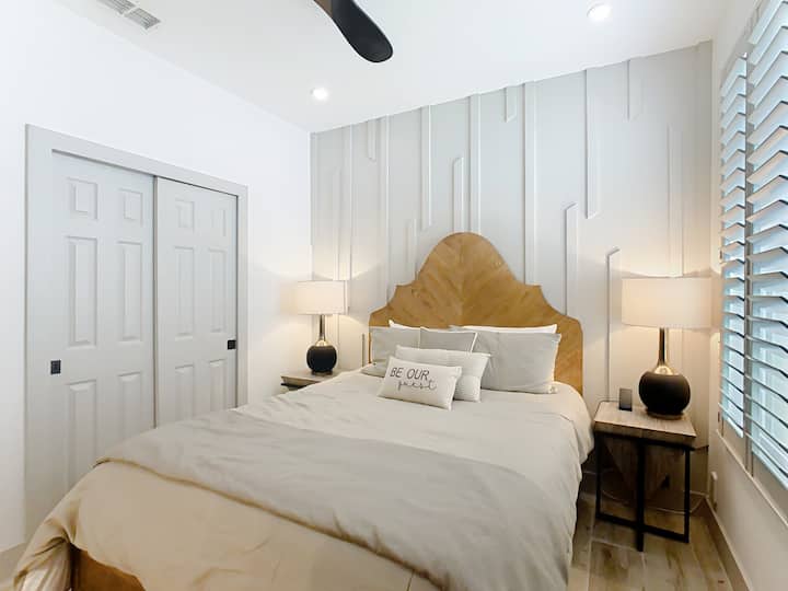 Svijetla i spokojna spavaća soba s drvenim uzglavljem izrađenim po mjeri i nježnim neutralnim tonovima.