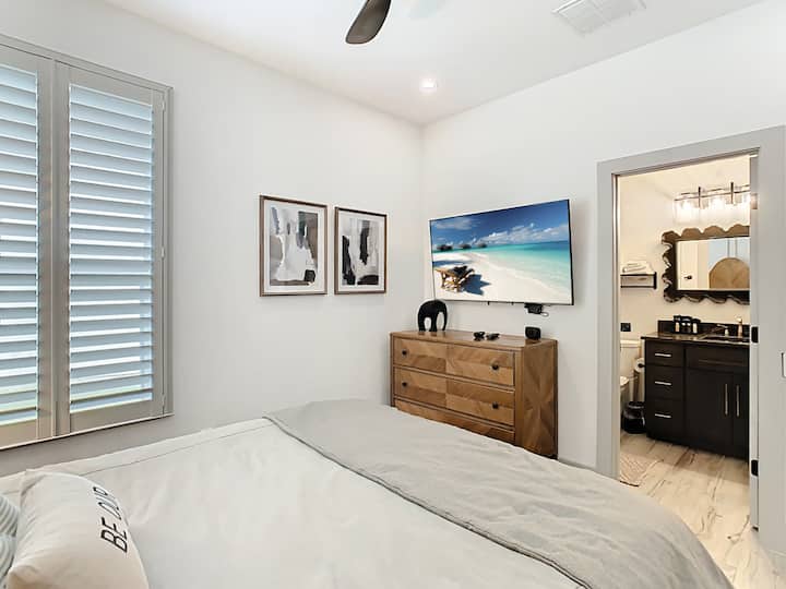 Prostrana spavaća soba s elegantnim obalnim umjetničkim djelima i pristupom privatnoj kupaonici.