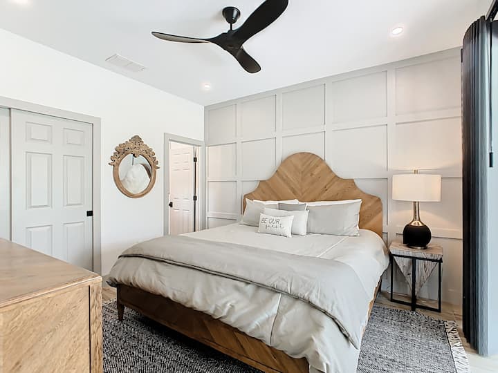 Elegantna spavaća soba s posebno izrađenim uzglavljem od drva, nježnim osvjetljenjem i opuštajućom atmosferom.