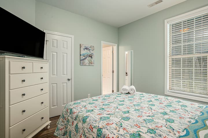 Une chambre avec un grand lit propre et moderne avec un décor de plage et tout ce dont vous avez besoin pour une nuit reposante.