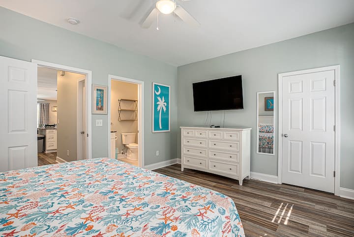 Une chambre principale avec très grand lit sur le rez-de-chaussée avec une salle de bain privée, beaucoup de rangement et une ambiance de plage fraîche.