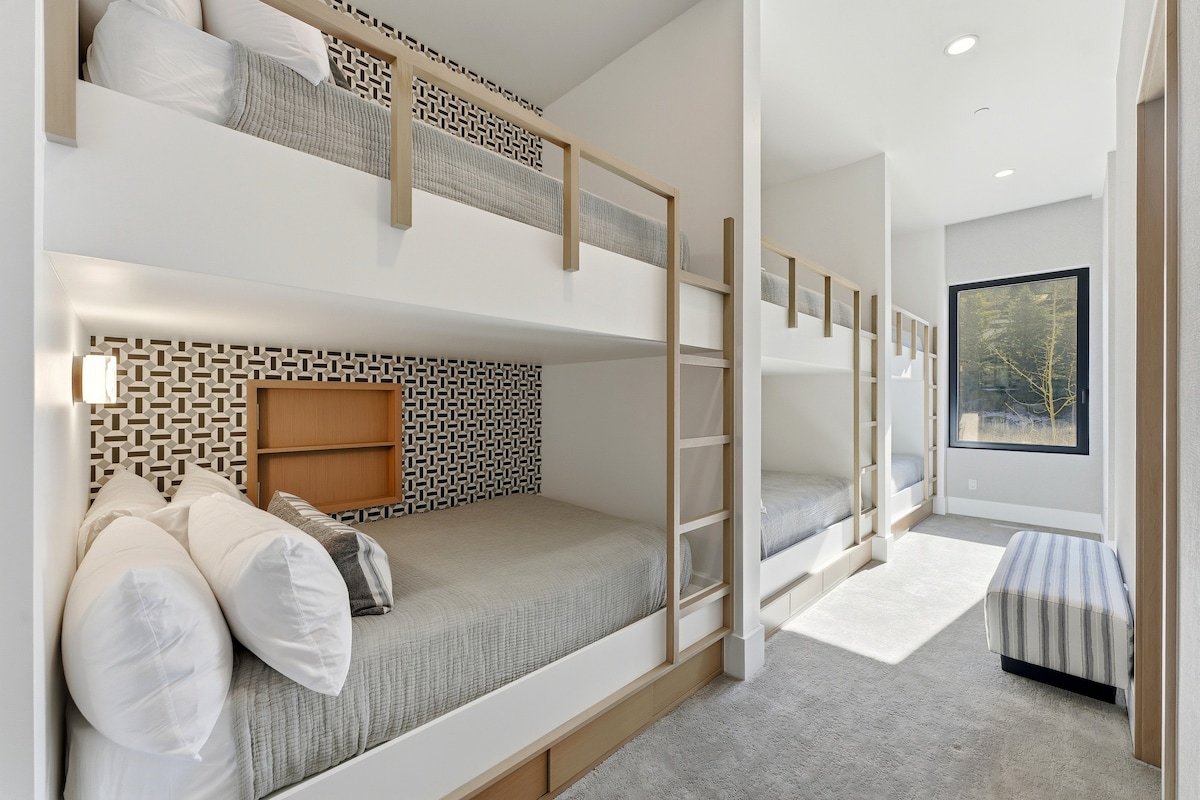 Suite con literas dobles incorporadas, papel tapiz atrevido y acogedor rincón de lectura, perfecto para niños o grupos.
