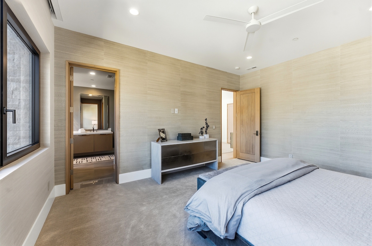 Suite de invitados con cama tamaño king, paredes texturizadas y baño en suite en un diseño cálido y terroso.