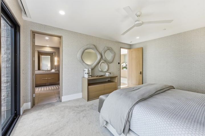 Elegantiški svečių apartamentai su karališko dydžio lova, abstrakčiais meno kūriniais ant sienų ir neutraliais atspalviais, iš kurių galima patekti į privačią lauko erdvę.