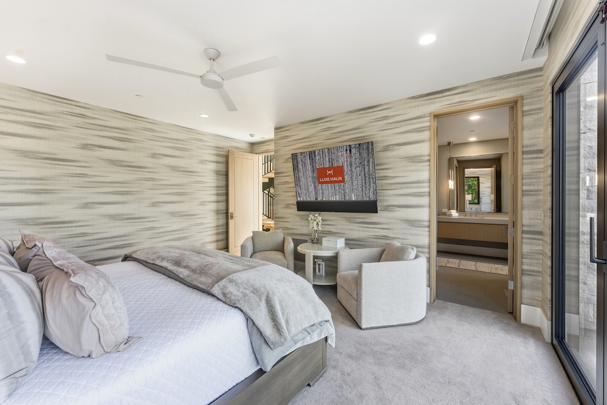 Acogedora y lujosa habitación con pared decorativa texturizada, TV de pantalla plana y salida al espacio exterior.