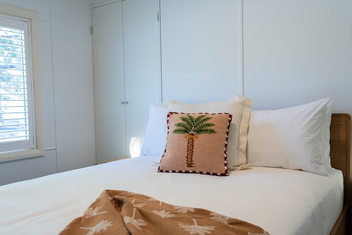Luminoso dormitorio costero con lujosa cama tamaño queen y amplio espacio de almacenamiento
