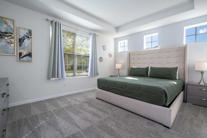 Suite principal serenity: iluminada por el sol y elegante con una lujosa cama tamaño king, alfombra suave y relajantes neutros, perfectos para noches de descanso.