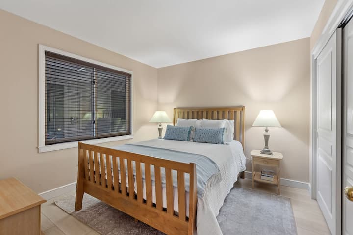 Habitación de invitados con cama de plataforma de madera con listones, dos lámparas de cabecera y pisos de aspecto de madera: cálida y relajante