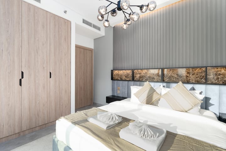 Elegante dormitorio con ropa de cama de alta calidad, armarios empotrados y luz natural suave.