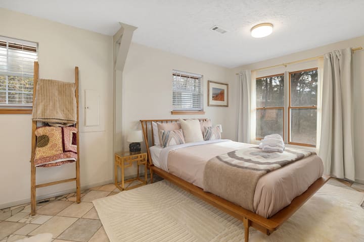 Arriba, hay un dormitorio con una cama tamaño queen, un armario y un baño cercano.