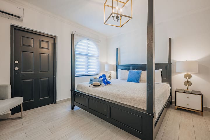 Apartman Master Suite 2 u The Tidesu s bračnim krevetom s okvirom od tamnog drveta i mirnim otočkim stilom.