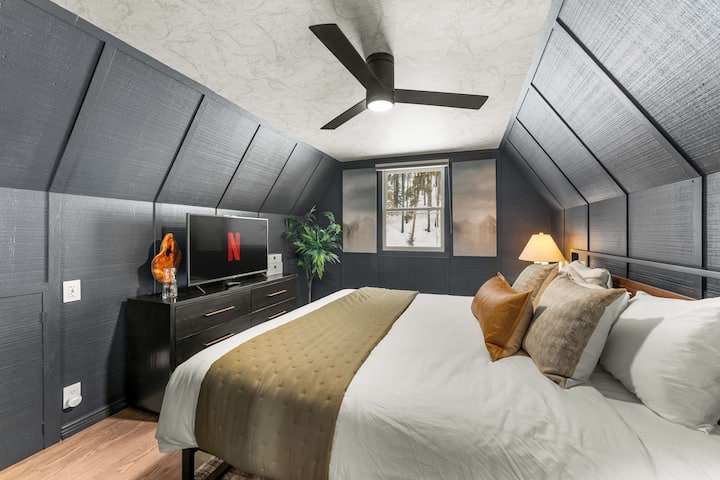 חדר שינה שלישי: כולל מיטת קינג סייז, תקרה משופעת ונעימה עם חיפוי עץ כהה וטלוויזיה חכמה לצפייה רגועה בשעות הלילה המאוחרות. כולל מאוורר תקרה ותאורה נדיבה לשהייה נוחה.