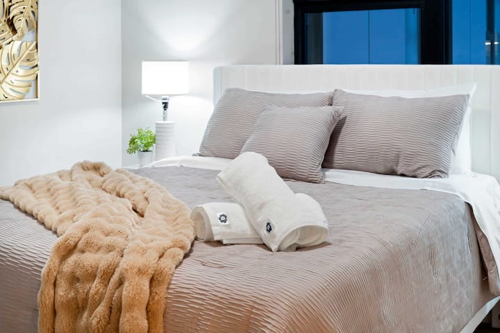 Escena de dormitorio tranquilo con ropa de cama en capas y tonos neutros suaves