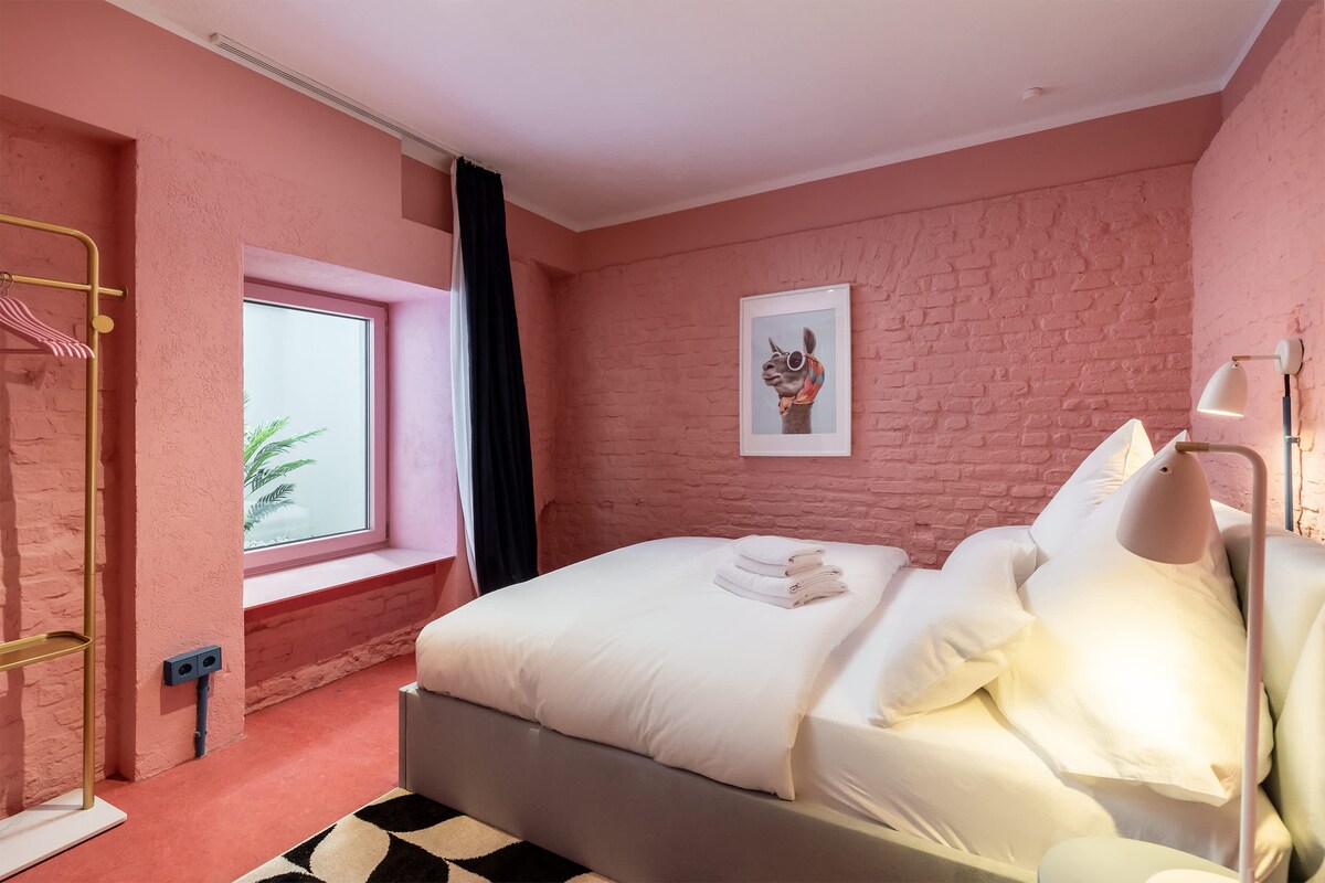 მთავარი საძინებელი, რომელიც გაფორმებულია ღია აგურით და მსუბუქი განათებით, შექმნილია კომფორტისა და დასვენებისთვის.