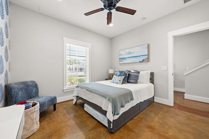 Bright coastal bedroom with queen bed, fan, and serene decor