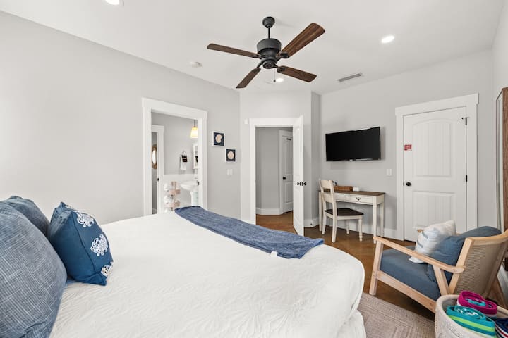Bright king suite with TV, desk, ceiling fan, and ensuite bath access