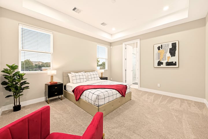 Vackert utformad primär svit med tak, stora fönster och direkt tillgång till ett modernt badrum.