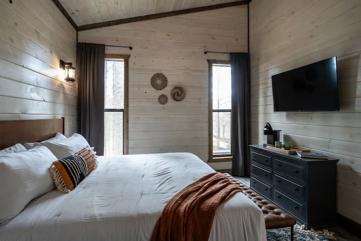 This king-sized bedroom with two large windows overlooks the home's elevated rear. They let in plenty of natural light and have blackout shades to help you sleep. Enjoy the smart TV, coffee station, and private ensuite bathroom.