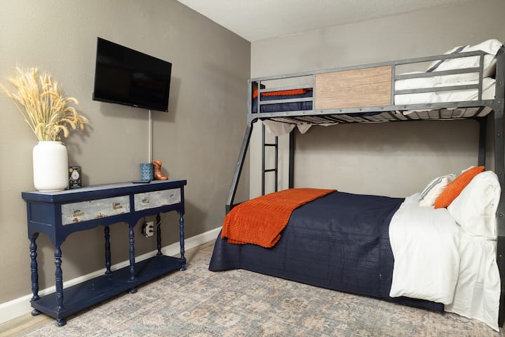 חדר שינה 2 יכול להכיל 3 אנשים עם מיטה מלאה ומיטת קומתיים - מושלם לילדים שחולקים או לחברים שמתגוררים יחד. טלוויזיה חכמה, שידת לילה ואירוח נעים עם מצעים בצבעי כחול כהה וכתום.