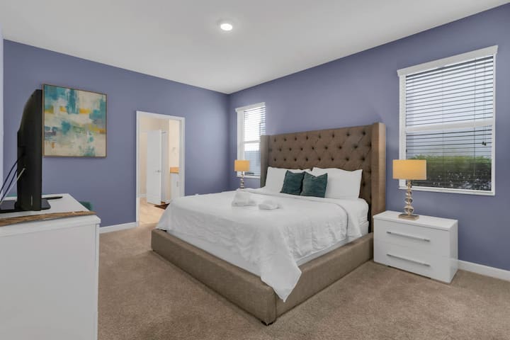 King bedroom with upholstered bed, nightstands, and television.