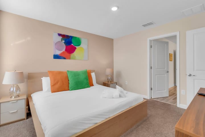 Queen bedroom with colorful accents and bedside tables.