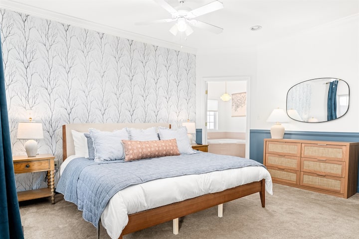 Спокойна основна спалня с голямо двойно легло, смарт телевизор Roku, плюшен разтегателен диван и големи прозорци, показващи спиращи дъха планински залези – вашето спокойно убежище с всички удобства.