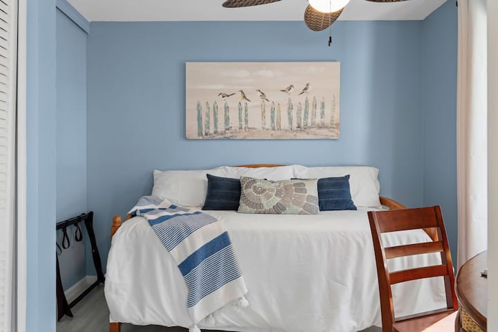 Habitación con sofá cama llena de luz con una suave decoración playera y sábanas de felpa: un espacio adicional acogedor para niños o adultos por igual.