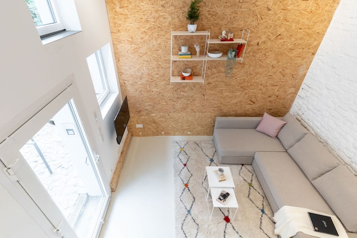 Un ángulo de arriba hacia abajo que muestra la sala de estar de planta abierta, los materiales naturales y el diseño escandinavo moderno.