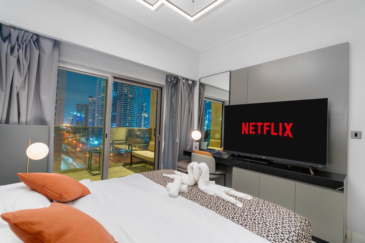 دعوة لفتح غرفة نوم ثانية على الشرفة، وعرض أضواء مدينة الخليج التجاري في المساء.