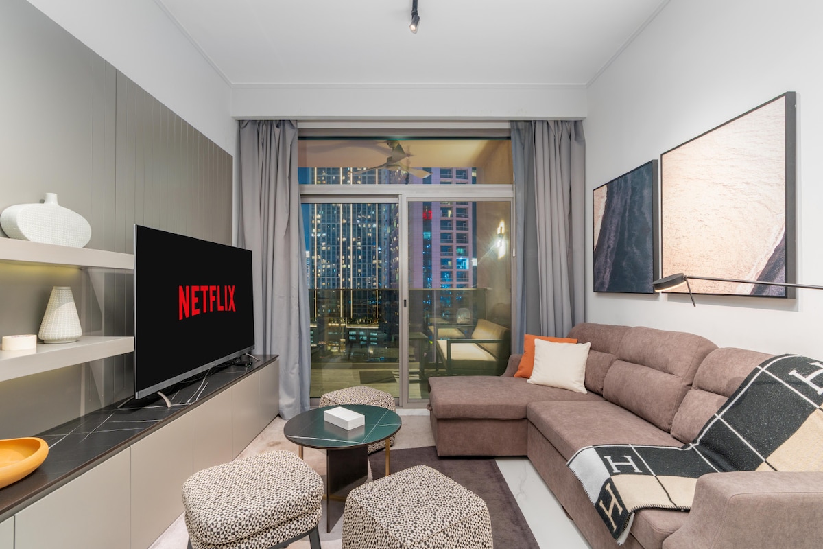 منطقة معيشة مشرقة مليئة بالضوء الطبيعي وإطلالات على المدينة، مما يخلق جوًا هادئًا وجذابًا.